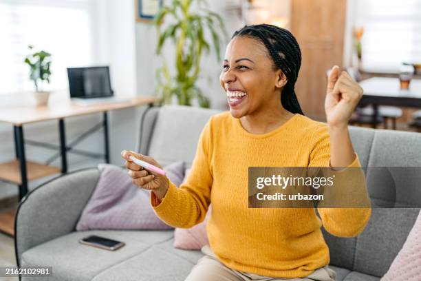 happy young woman taking a pregnancy test at home - ovulation stock pictures, royalty-free photos & images
