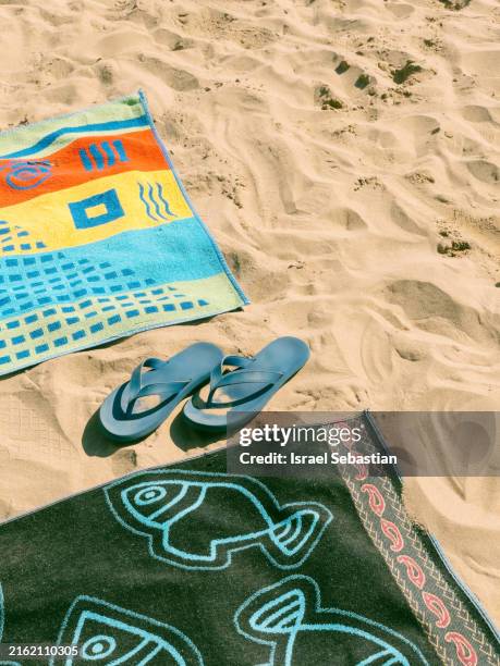 beach towels and flip flops lying on sand - ciabatta infradito foto e immagini stock