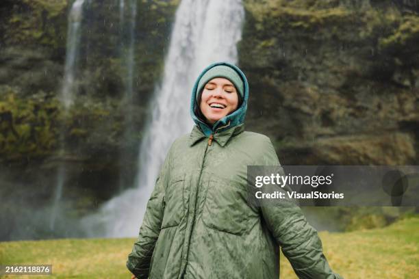 happy woman contemplating dramatic natural landscapes with waterfall view - hygge stock pictures, royalty-free photos & images