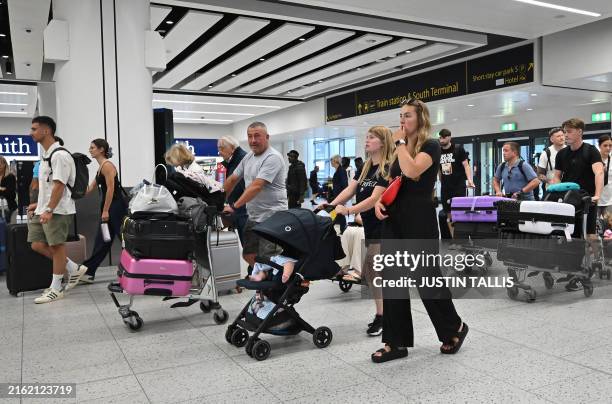 Passengers arrive in the check-in area of Gatwick Airport as some flights are cancelled or delayed, in Horley, south of London on July 20, 2024.