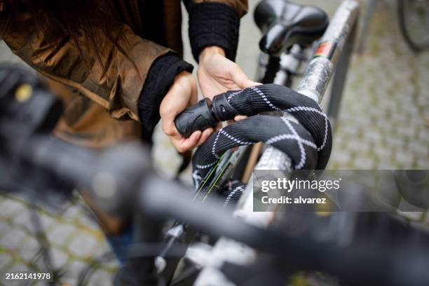 nahaufnahme einer pendlerin, die ihr fahrrad in der stadt an einen metallständer anbindet - fahrradschloss stock-fotos und bilder