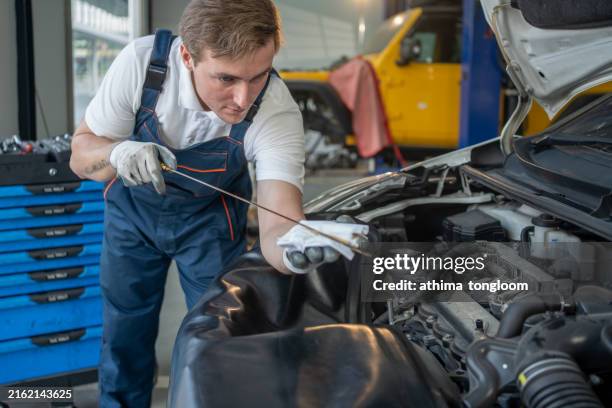 checking oil in car engine at car service center. - oil change stock pictures, royalty-free photos & images