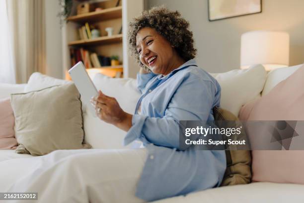 mujer descansando en casa y usando tableta digital en casa - lector de libros electrónicos fotografías e imágenes de stock
