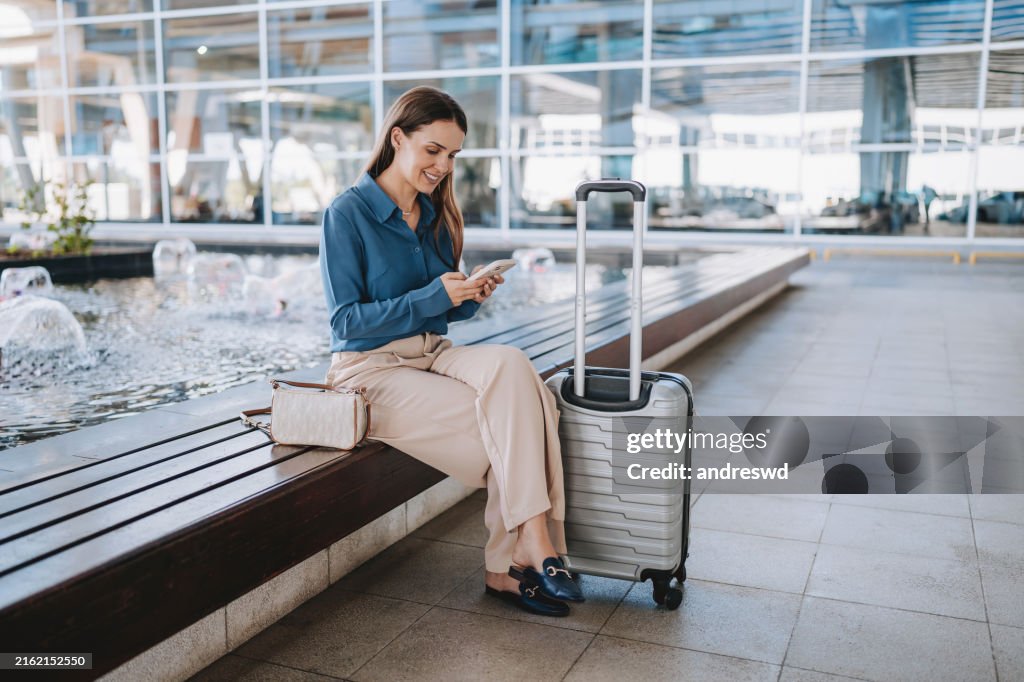 Una mujer en el aeropuerto usando un teléfono inteligente