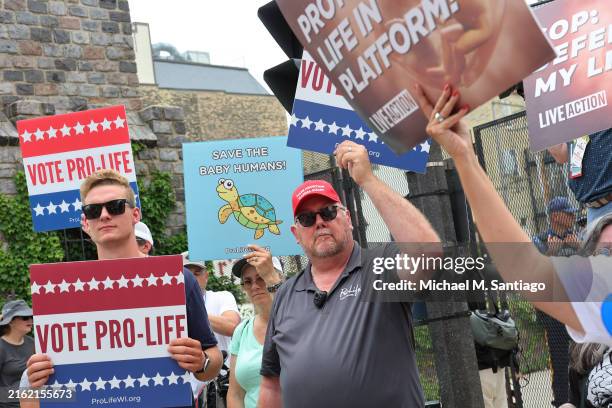 Anti-abortion protesters hold signs as they watch people participate in the Coalition to March on the RNC near the Fiserv Forum on July 15, 2024 in...