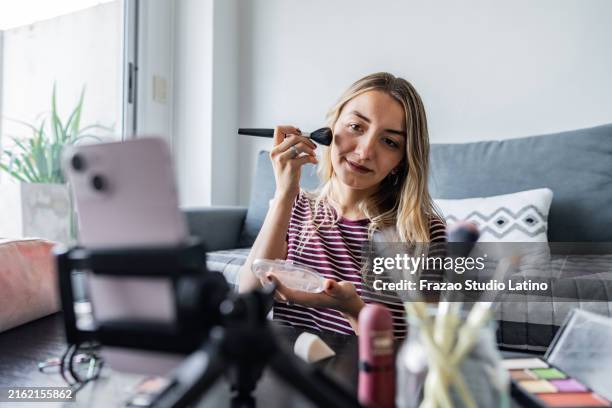 woman vlogging makeup tutorial recording on mobile phone at home - self employment stock pictures, royalty-free photos & images