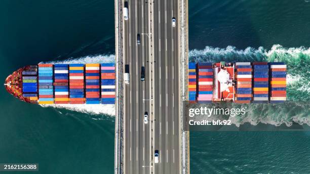 aerial view of a cargo ship passing under bridge. cargo ship beneath bridge. - nautische ausrüstung stock-fotos und bilder