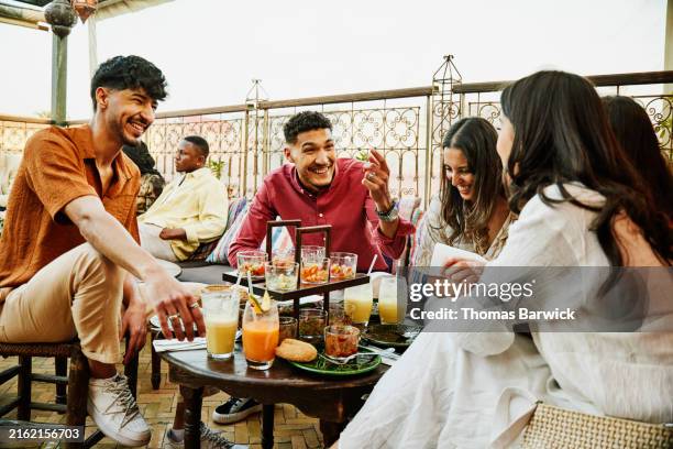 medium wide shot friends sitting at rooftop restaurant in marrakech - sans alcool photos et images de collection