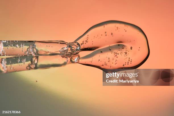 pipette with a drop of facial serum on an orange gradient background. - face serum stock pictures, royalty-free photos & images