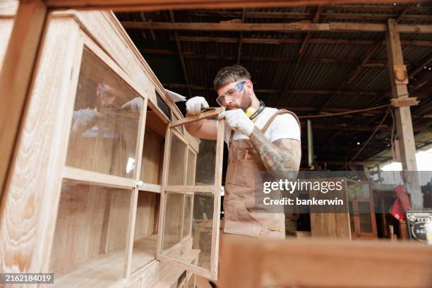 young carpenter measure cupboard in factory - cupboard stock pictures, royalty-free photos & images