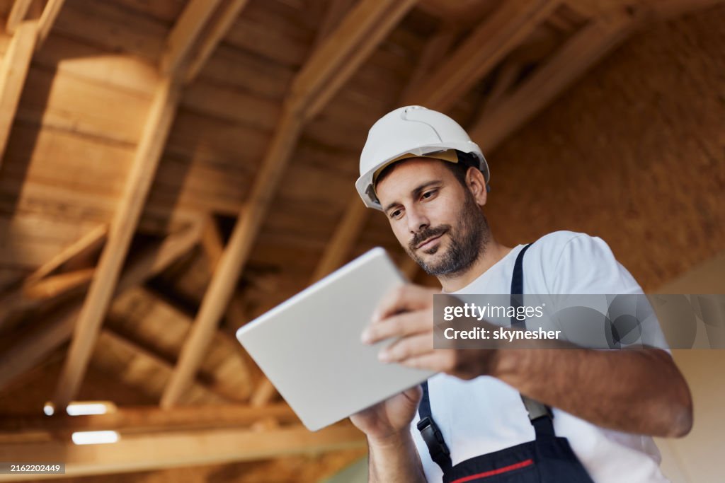 Below view of manual worker using touchpad at construction site.