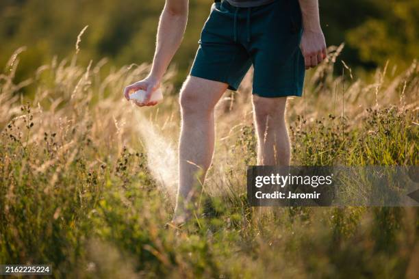 man while applying insect repellent - inseto imagens e fotografias de stock
