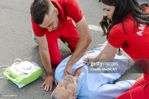 doctors providing first aid to the patient on the street - defibrillator street stock pictures, royalty-free photos & images