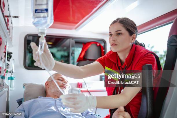 sanitäterin, die dem patienten im krankenwagen medizinische hilfe leistet - befreiung stock-fotos und bilder