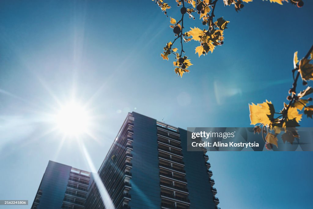 High-rise building against background of bright sun in cloudless blue sky. climate change, abnormal heat
