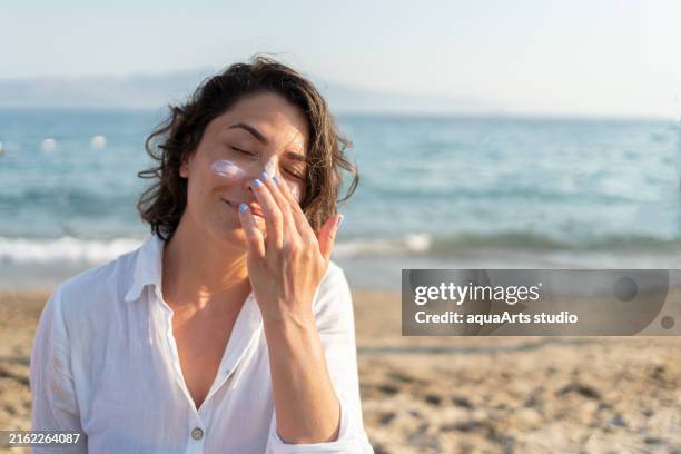 applying sunscreen cream at the sea on summer holiday - vitamine d stockfoto's en -beelden