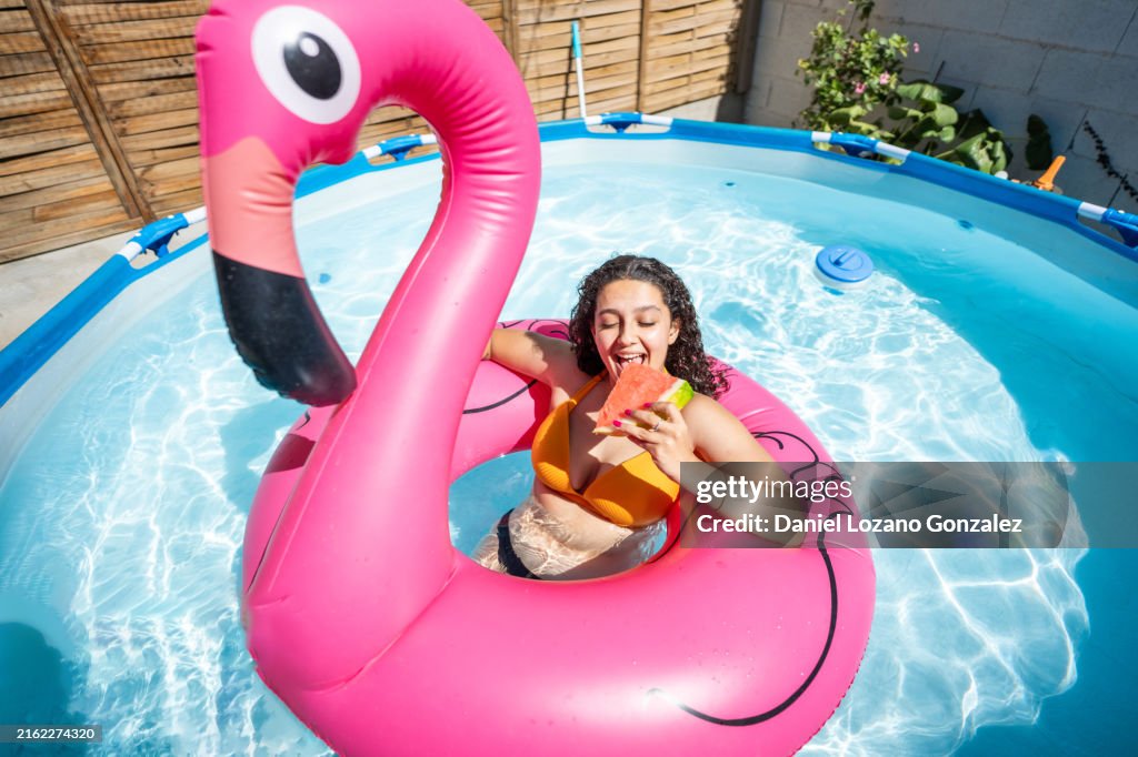 Young woman enjoying watermelon in inflatable flamingo pool float