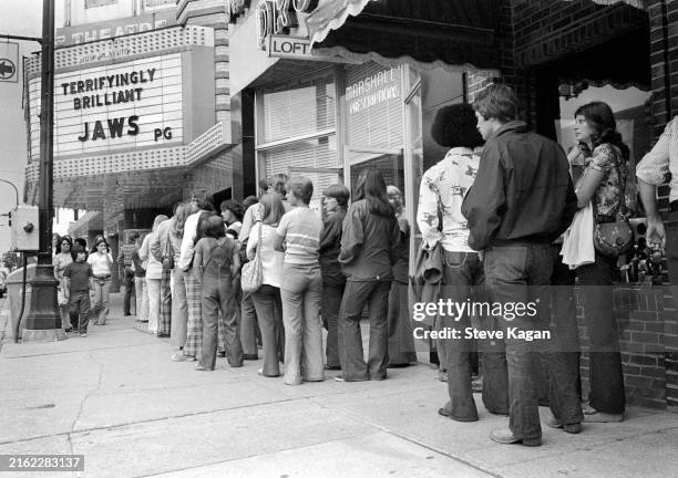 View of a line of moviegoers outside the State Theatre , Ann Arbor, Michigan, July 14, 1975. The cinema marquee advertises the film 'Jaws.'