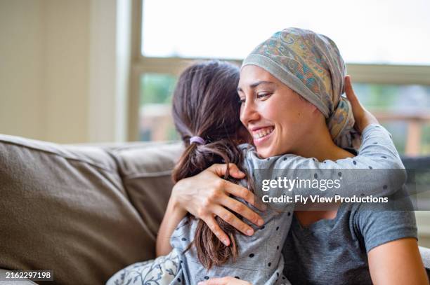 woman living with cancer hugs young daughter - head tie stock pictures, royalty-free photos & images