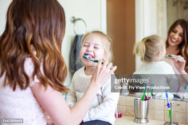 une mère aide sa fille en bas âge à se brosser les dents - se brosser les dents photos et images de collection