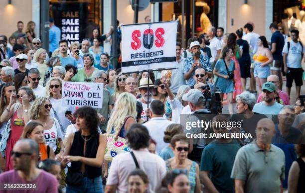 Protesters hold a banner which reads as "SOS Residents" as they take part in a demonstration against overtourism and housing prices on the island of...