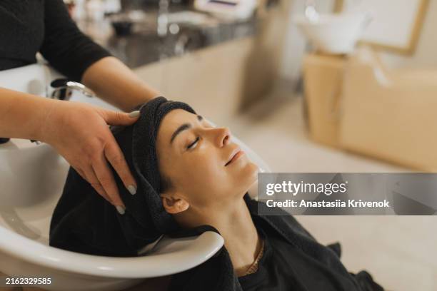 woman in hair salon getting hair washed. - salone di parrucchiere foto e immagini stock