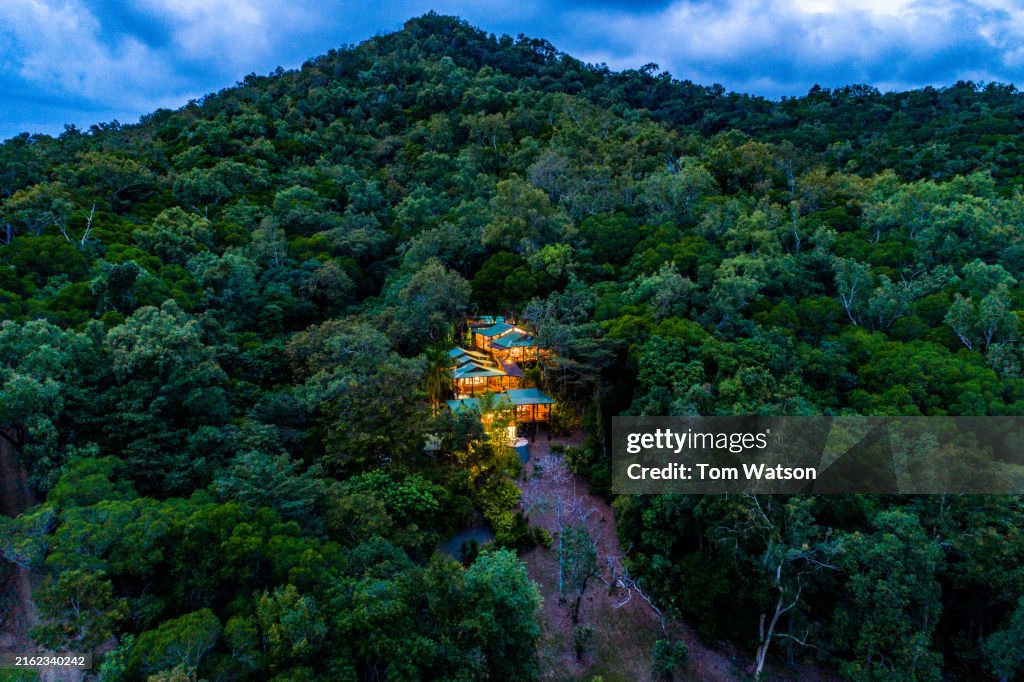 Aerial View of Illuminated Cabins Nestled in Mowbray's Lush Rainforest at Dusk