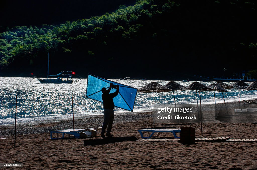 A man carrying a blue beach umbrella on Adrasan beach