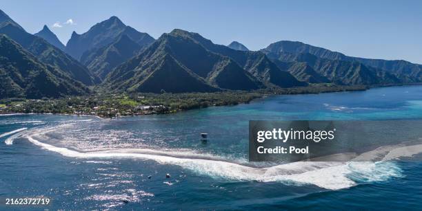 An aerial view shows the athletes taking part in a surfing training session in Teahupo'o, ahead of the start of the Paris 2024 Olympic Games on the...