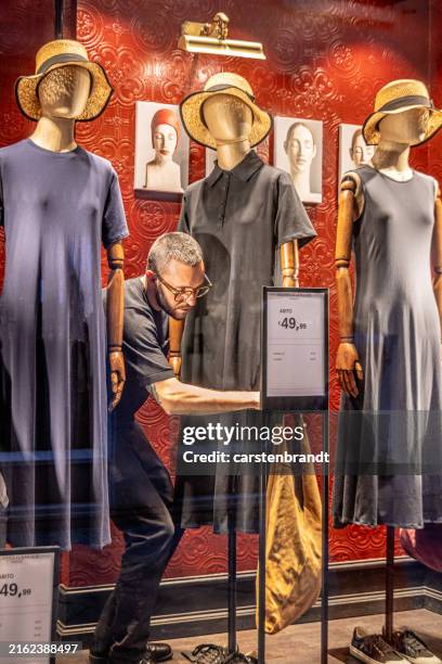 mann schmückt schaufensterpuppen in einem schaufenster - kleiderpuppe stock-fotos und bilder