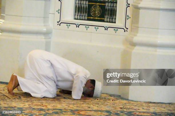 during prayer, a man kneels and touches the carpet with his head in the sultan qaboos grand mosque, muscat sultanate of oman - kneeling stock pictures, royalty-free photos & images