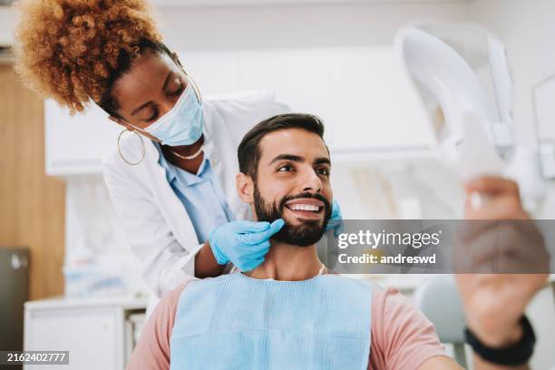 trattamento dentale uomo con dentista donna che guarda allo specchio - sbiancamento dentale foto e immagini stock