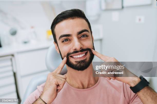 uomo che mostra i denti nello studio dentistico - denti umani foto e immagini stock