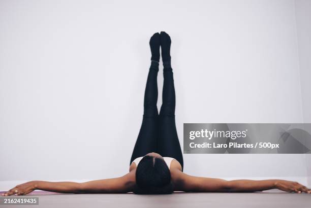 woman exercising against white wall stretching exercises on yoga mat,corpus christi,texas,united states,usa - füße hochlegen stock-fotos und bilder