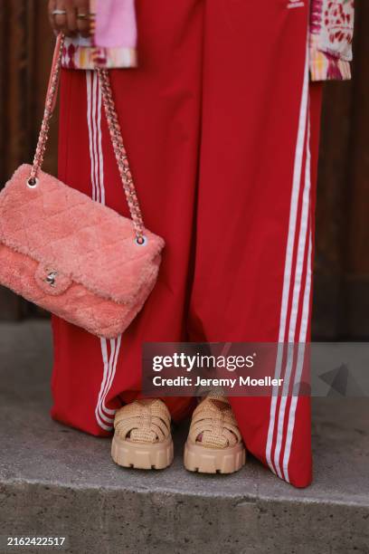 Karin Teigl is seen wearing a floral, multi-color, long, opened shirt from Etro; a coral, fluffy bag from Chanel; wide track pants in red from...
