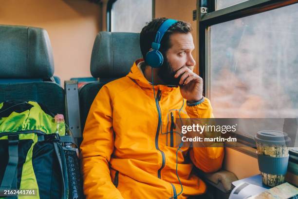 tourist man listening to music in the train - listening stock pictures, royalty-free photos & images
