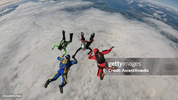 freefall jumpers hold hands mid-air - skydiving pov stock pictures, royalty-free photos & images