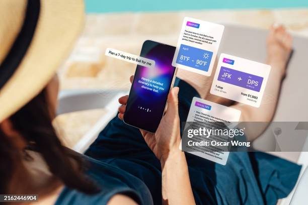 over the shoulder view of young asian woman using virtual assistance technology on smart phone to plan a trip - inquadratura da sopra le spalle foto e immagini stock