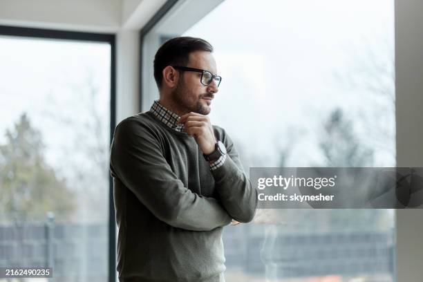 hombre despreocupado soñando despierto junto a la ventana. - introspección fotografías e imágenes de stock