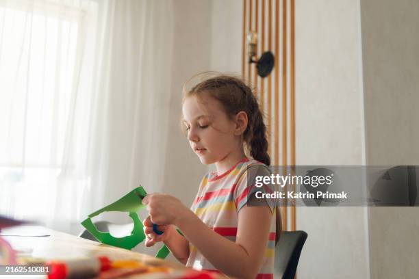 a child is doing creative work, a girl is cutting out colored paper with scissors - glue stock pictures, royalty-free photos & images