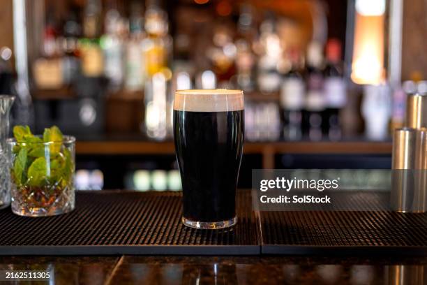pint of irish stout standing on a bar - cerveja amarga imagens e fotografias de stock