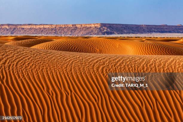sand dunes in desert in front of tuwaiq mountain landscape, central arabia, saudi arabia - escarpment stock pictures, royalty-free photos & images