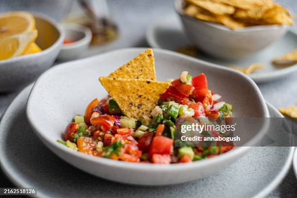 close-up of a bowl of traditional mexican pico de gallo salsa with tortilla chips and fresh lemon - salsa sauce stock pictures, royalty-free photos & images