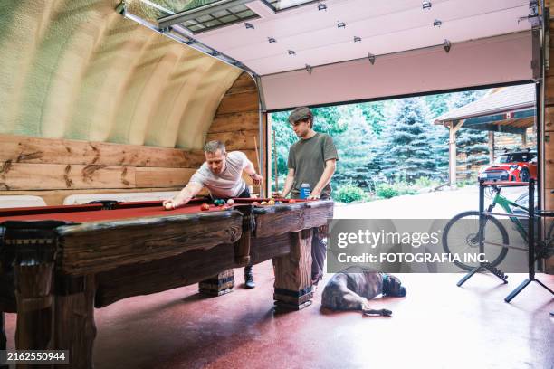 two young man playing pool in man cave - man cave stock pictures, royalty-free photos & images