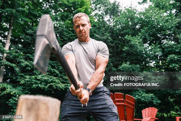 young man chopping wood with axe - lumberjack stock pictures, royalty-free photos & images