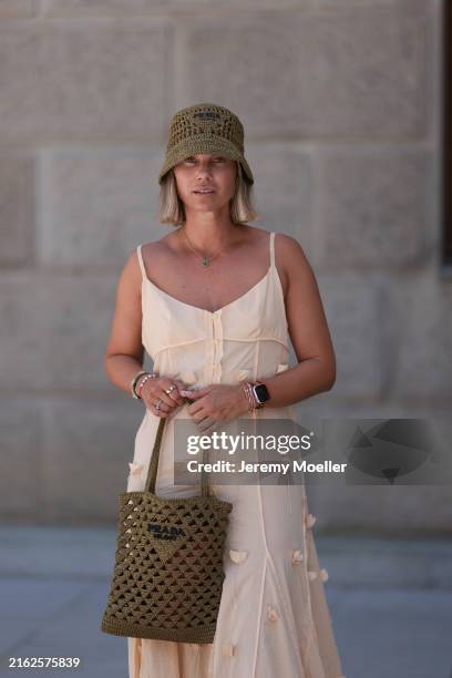 Karin Teigl is seen wearing a woven raffia hat in olive from Prada; a yellow-gold “Alhambra” necklace with green pendant in cloverleaf shape from Van...