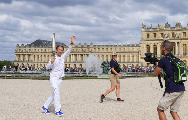 Torch relay runner passes by the Chateau de Versailles near Paris on July 23 three days ahead of the opening ceremony of the Paris Olympics.