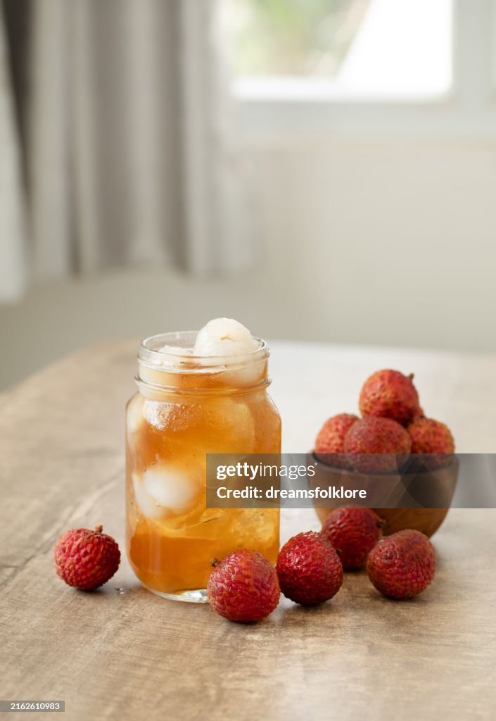 Glass of ice lychee tea garnish with Fresh Lychee, with Fresh Lychee Fruits on the side . Perfect summer drinks