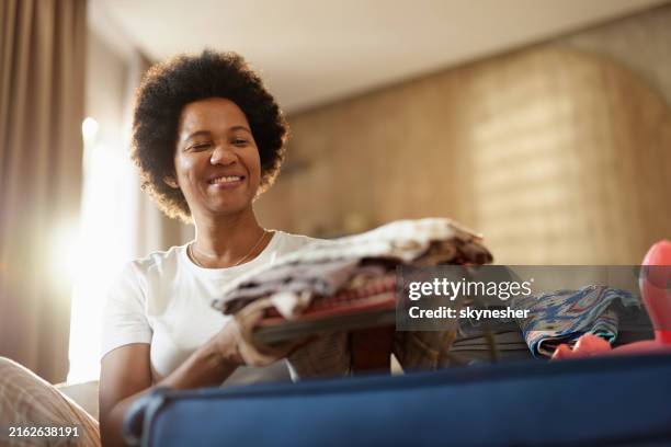 happy black woman packing her luggage at home. - travel essentials stock pictures, royalty-free photos & images