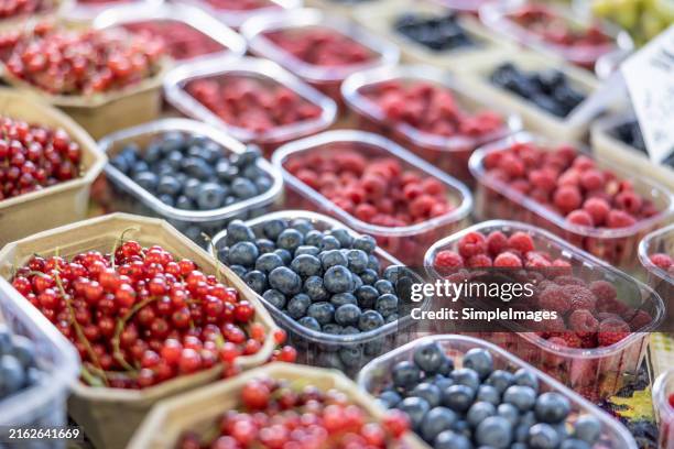 fresh organic raspberries, currants and blueberries on stall for sell in marketplace - berry fruit stock pictures, royalty-free photos & images